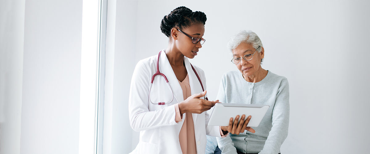 Woman looking at a tablet with her physician.