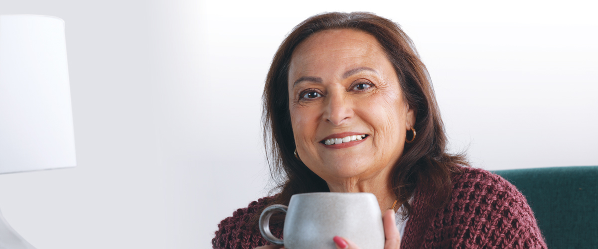 Senior woman smiling and holding a cup of coffee