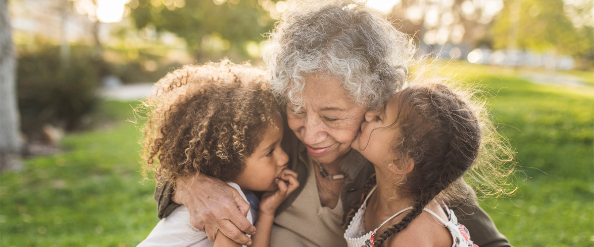 Woman hugging grandchildren outside.