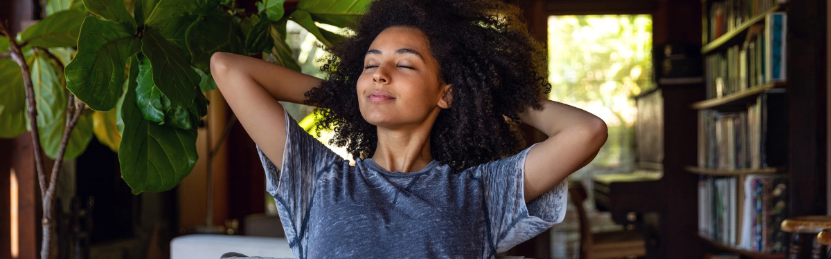 Woman relaxing, sitting in a chair with her hands behind her head.