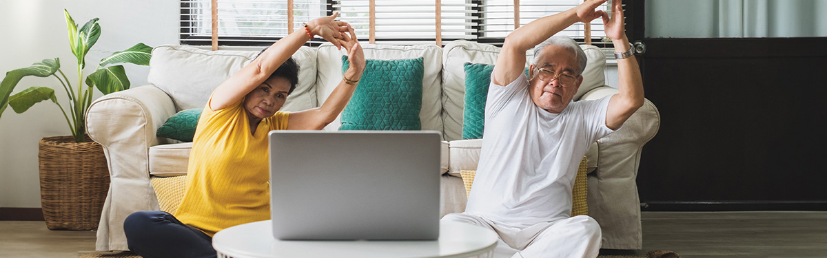 Man and woman stretching in front of a laptop.