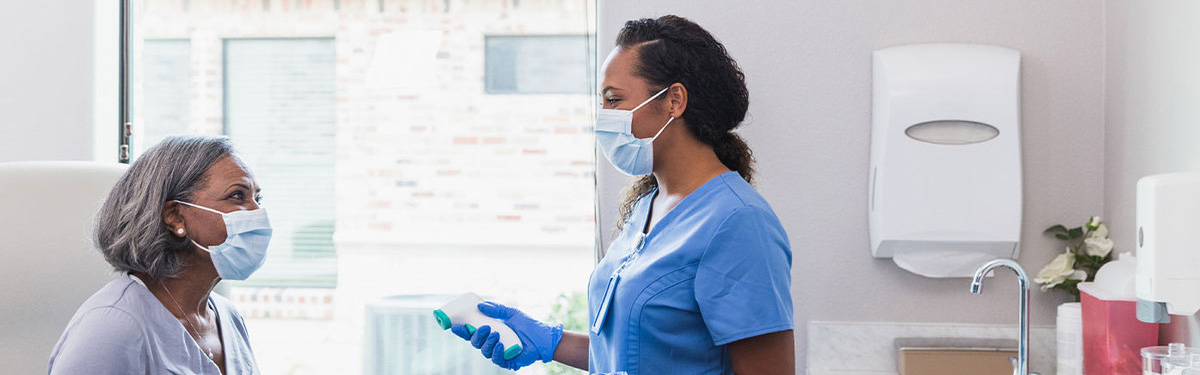 Medical professional taking  a woman's temperature in a doctor's office.