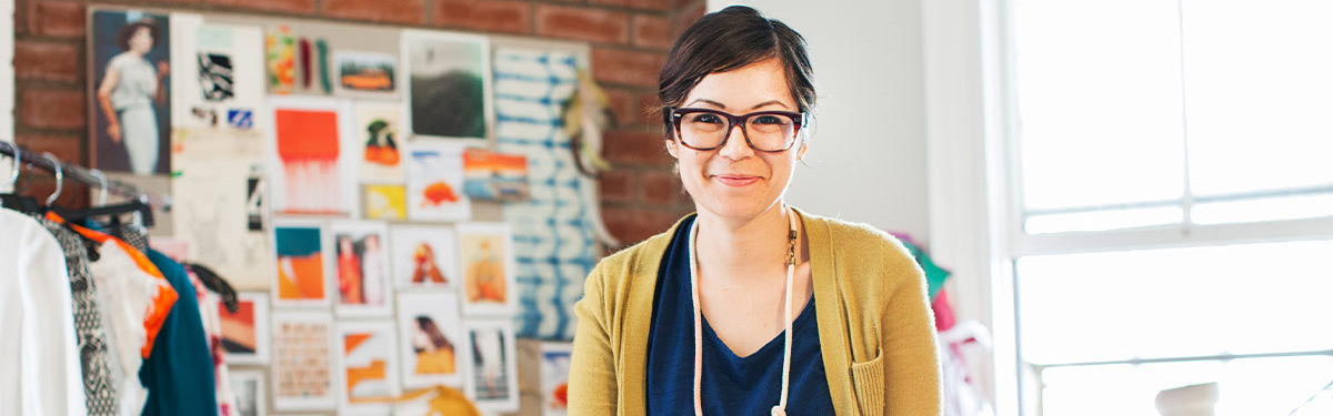 Woman smiling next to a rack of clothing.