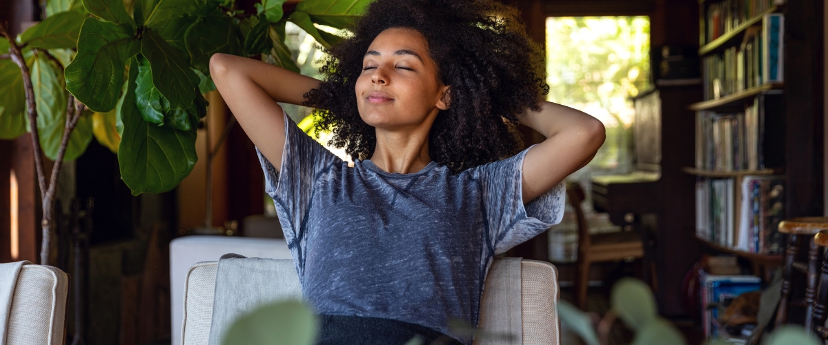 Woman relaxing, sitting in a chair with her hands behind her head.