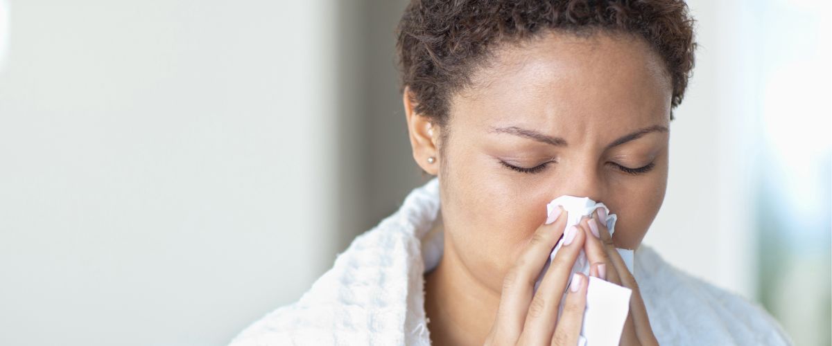 Woman blowing her nose into a tissue.